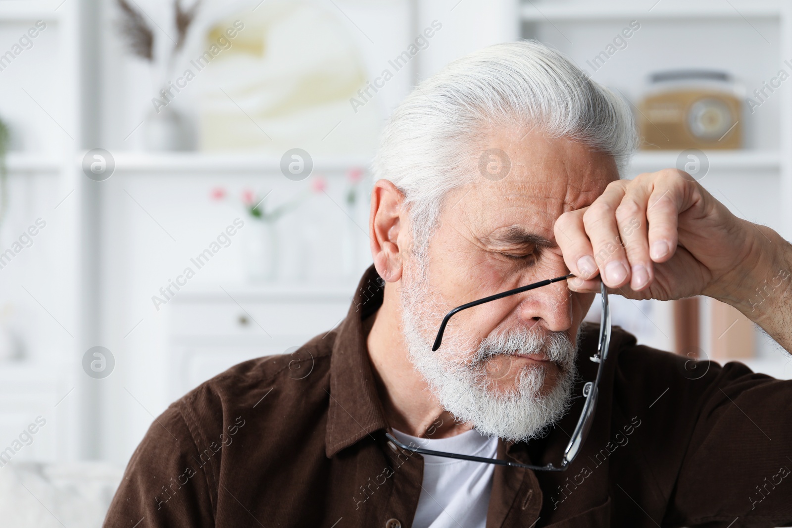 Senior man suffering from eyestrain at home Photo of Senior man suffering from eyestrain at home