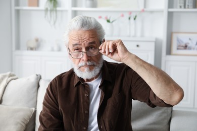 Photo of Senior man with vision problem on sofa at home