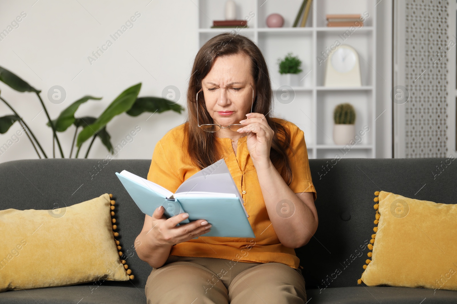 Woman with vision problem reading book on sofa at home Photo of Woman with vision problem reading book on sofa at home