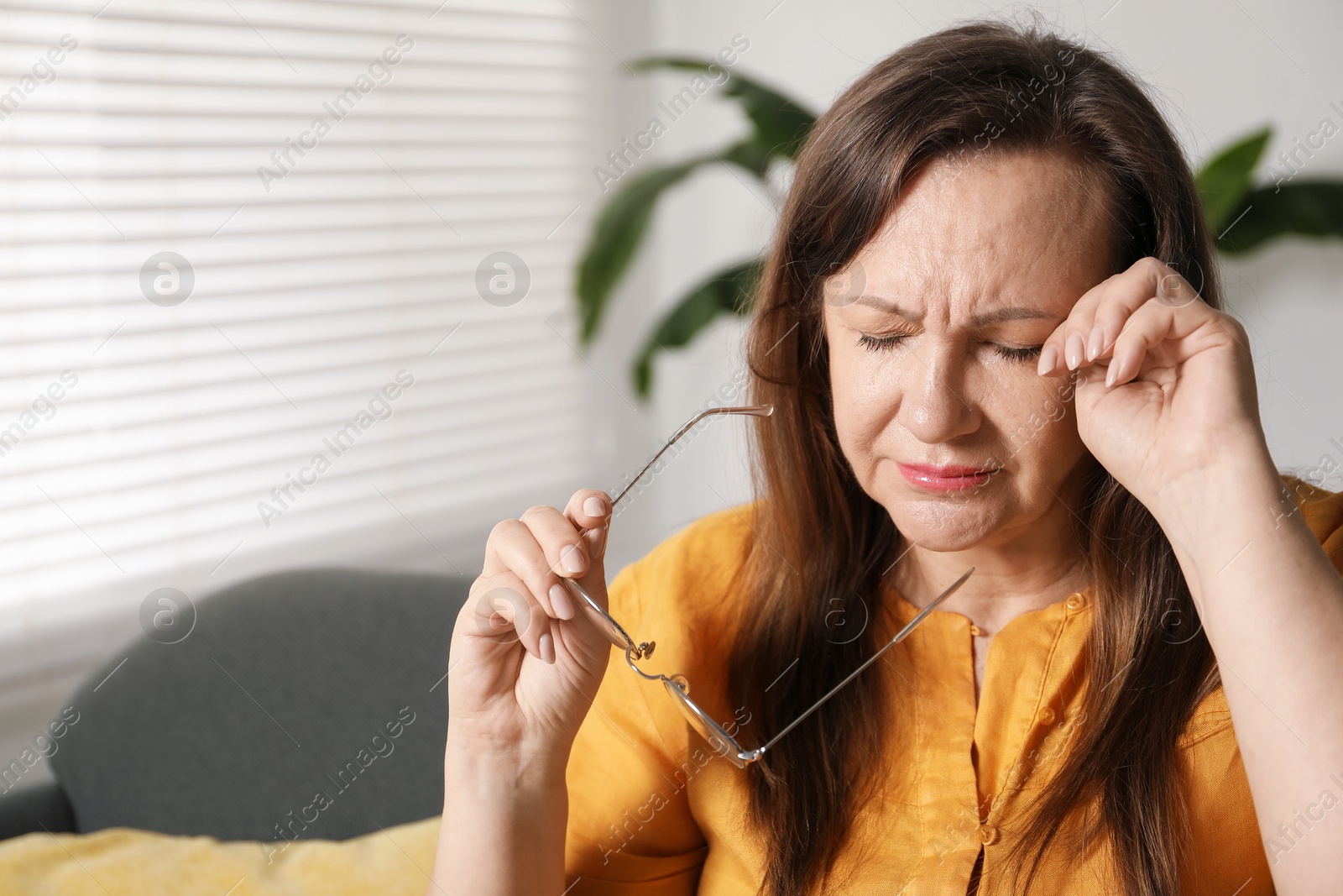 Woman with glasses suffering from eyestrain on sofa at home, space for text Photo of Woman with glasses suffering from eyestrain on sofa at home, space for text