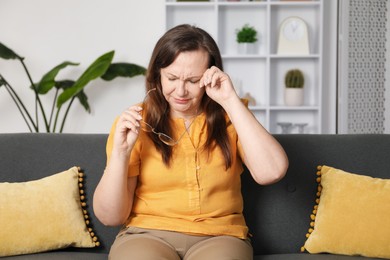 Photo of Woman with glasses suffering from eyestrain on sofa at home