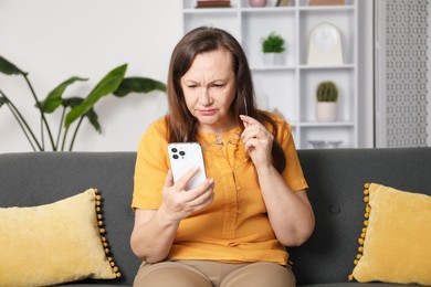 Photo of Woman with vision problem using smartphone on sofa at home