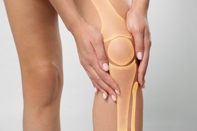 Image of Anatomy of knee. Woman with illustration on her leg against grey background, closeup