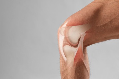 Image of Anatomy of knee. Man with illustration on his leg against grey background, closeup. Space for text