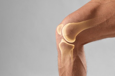 Image of Anatomy of knee. Man with illustration on his leg against grey background, closeup. Space for text