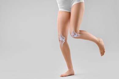 Image of Anatomy of knee. Woman running against grey background, closeup. Illustration on her leg