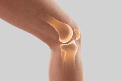Image of Anatomy of knee. Woman with illustration on her leg against grey background, closeup