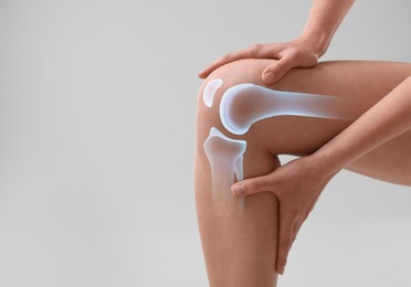 Image of Anatomy of knee. Woman with illustration on her leg against grey background, closeup. Space for text