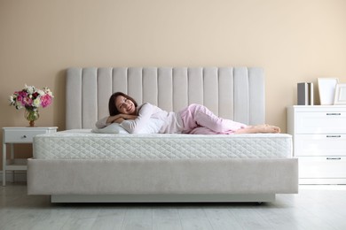 Photo of Woman lying on bed with orthopedic mattress at home