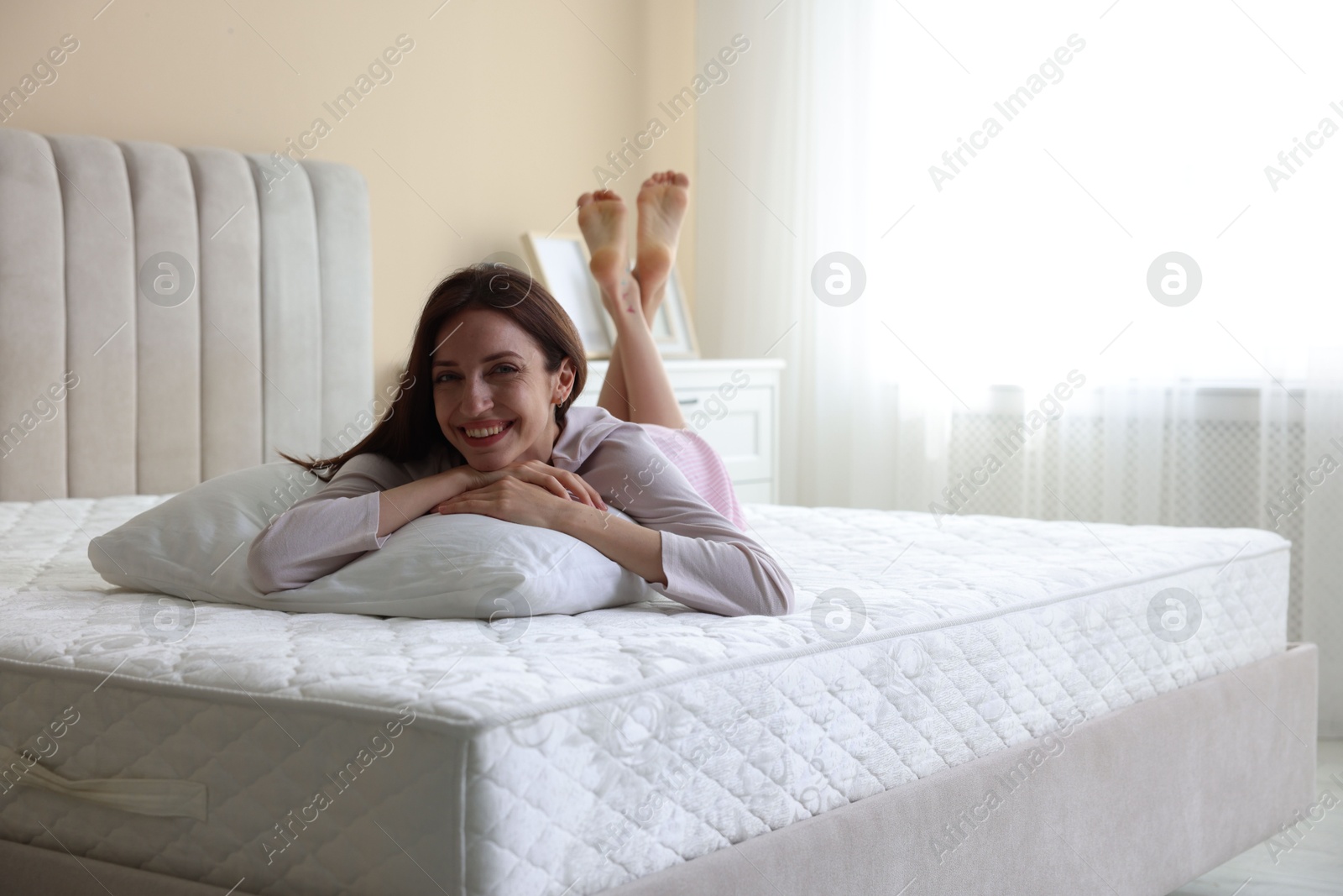 Woman lying on bed with orthopedic mattress at home. Space for text Photo of Woman lying on bed with orthopedic mattress at home. Space for text
