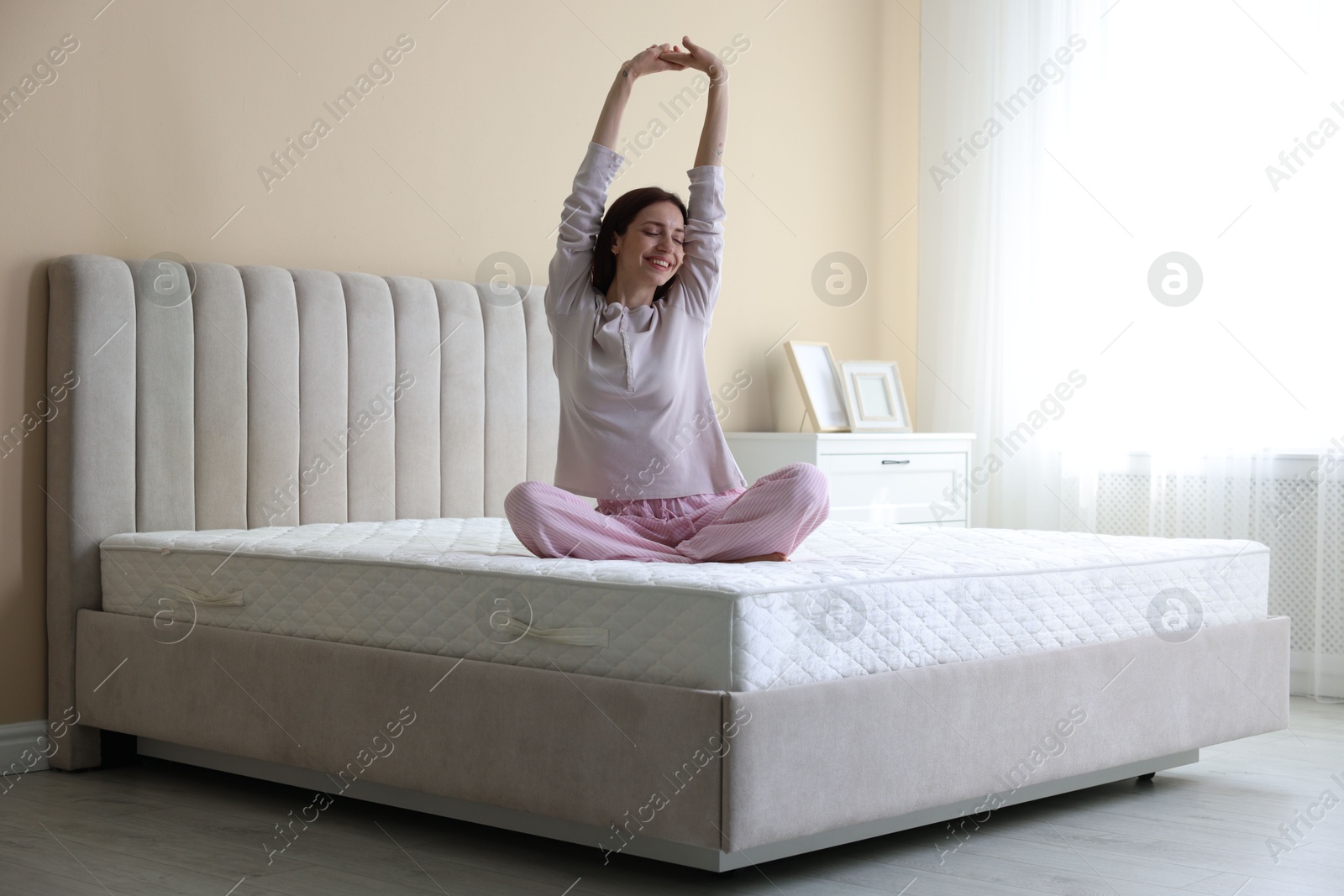 Woman stretching on bed with orthopedic mattress at home Photo of Woman stretching on bed with orthopedic mattress at home
