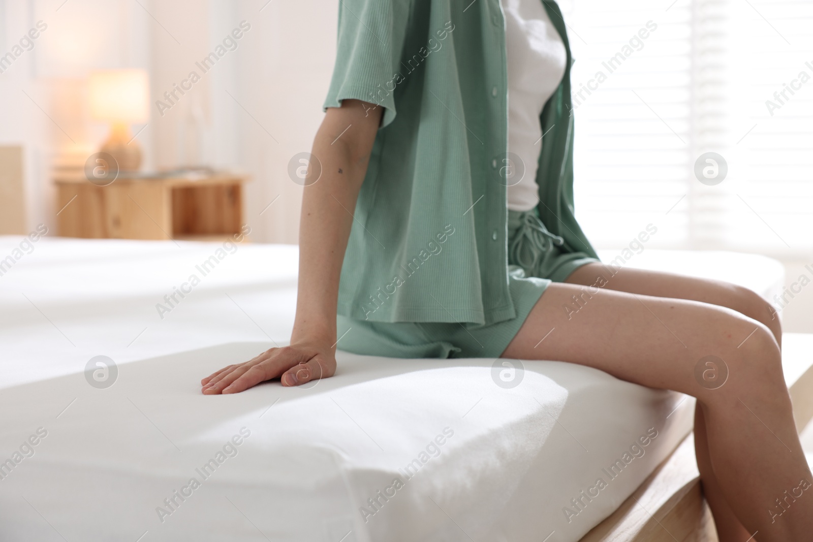 Woman on bed with soft mattress at home, closeup Photo of Woman on bed with soft mattress at home, closeup
