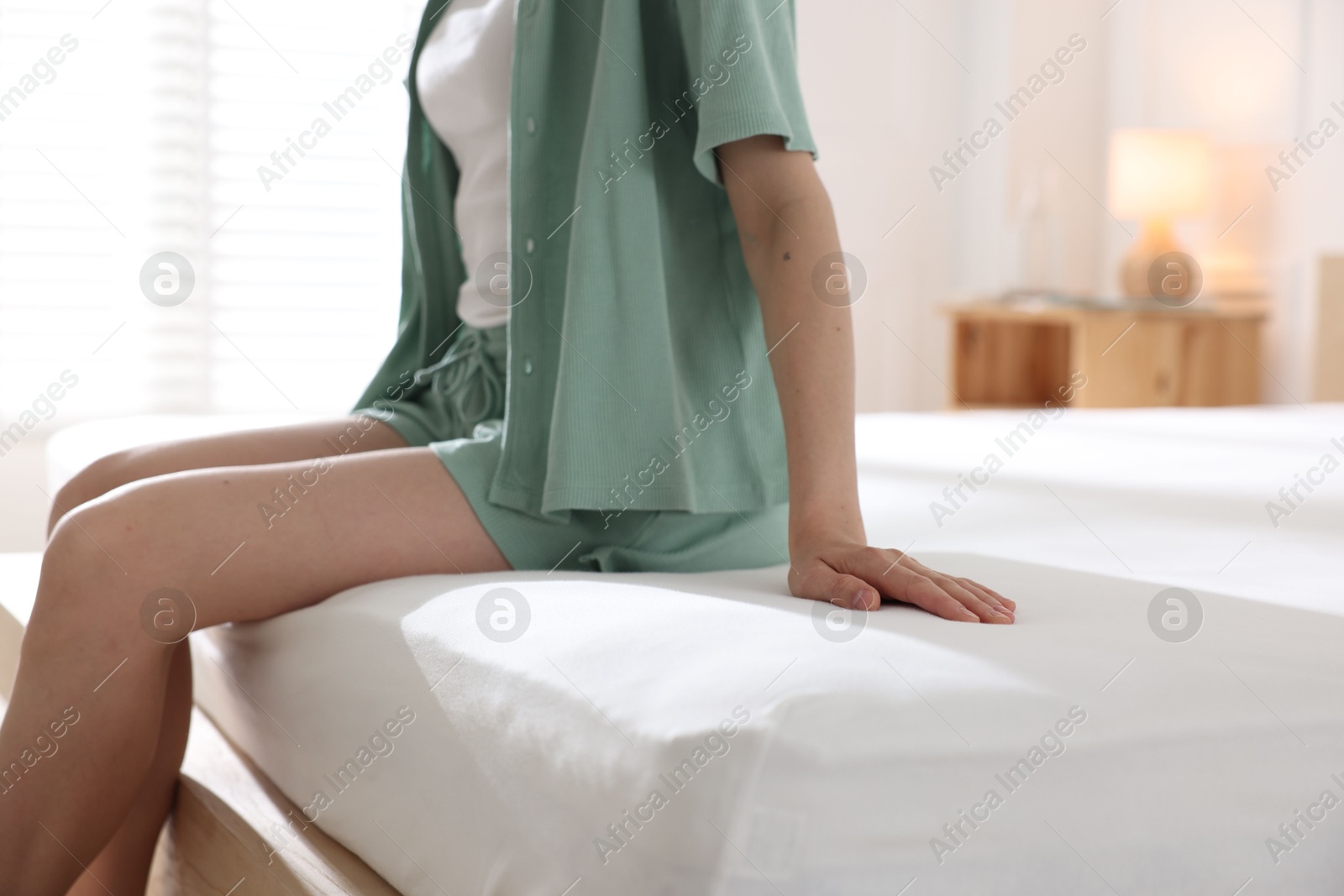 Woman on bed with soft mattress at home, closeup Photo of Woman on bed with soft mattress at home, closeup