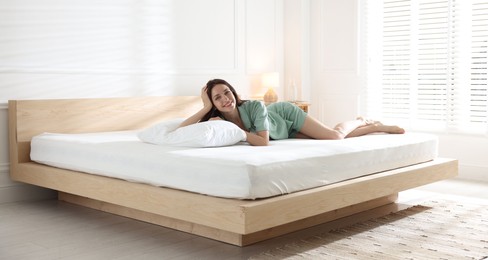 Photo of Woman lying on bed with orthopedic mattress at home