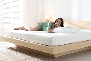 Photo of Woman lying on bed with orthopedic mattress at home