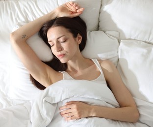 Photo of Woman sleeping on bed with soft mattress at home, top view