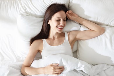 Photo of Woman sleeping on bed with soft mattress at home, top view