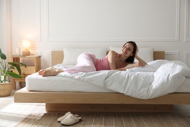 Photo of Woman lying on bed with soft mattress at home