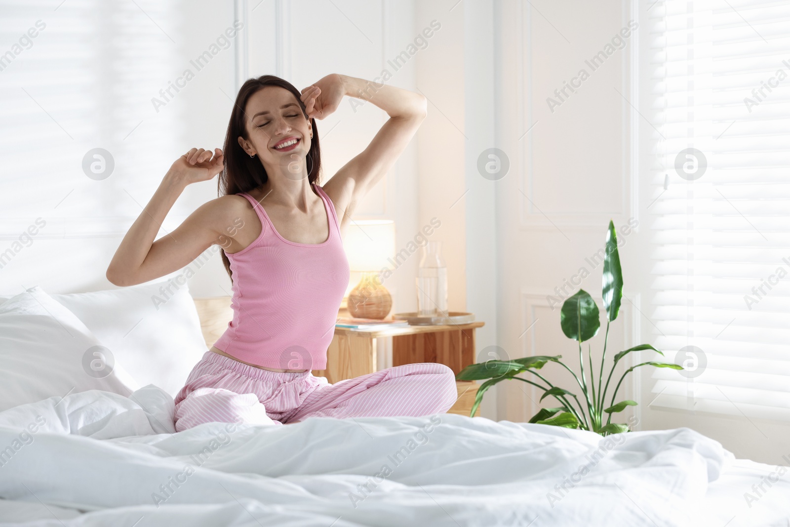 Woman stretching on bed with soft mattress at home. Space for text Photo of Woman stretching on bed with soft mattress at home. Space for text