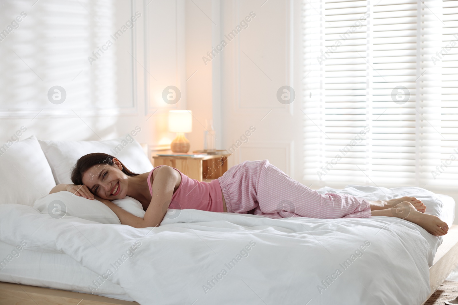 Woman lying on bed with soft mattress at home. Space for text Photo of Woman lying on bed with soft mattress at home. Space for text