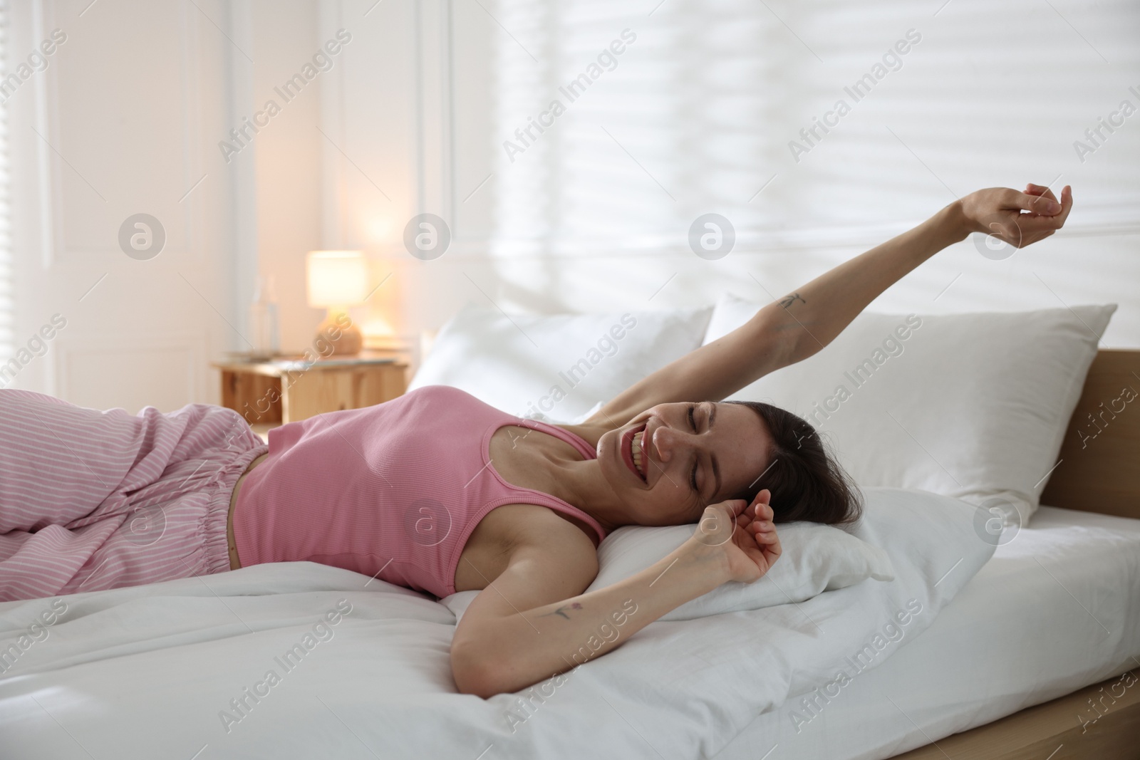 Woman stretching on bed with soft mattress at home Photo of Woman stretching on bed with soft mattress at home
