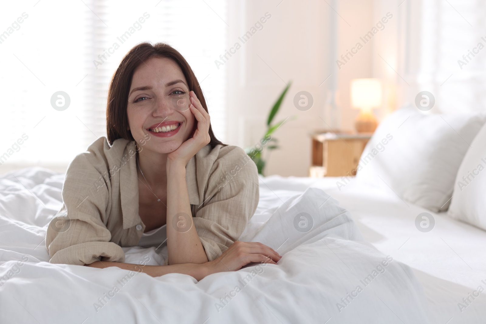 Woman lying on bed with soft mattress at home. Space for text Photo of Woman lying on bed with soft mattress at home. Space for text