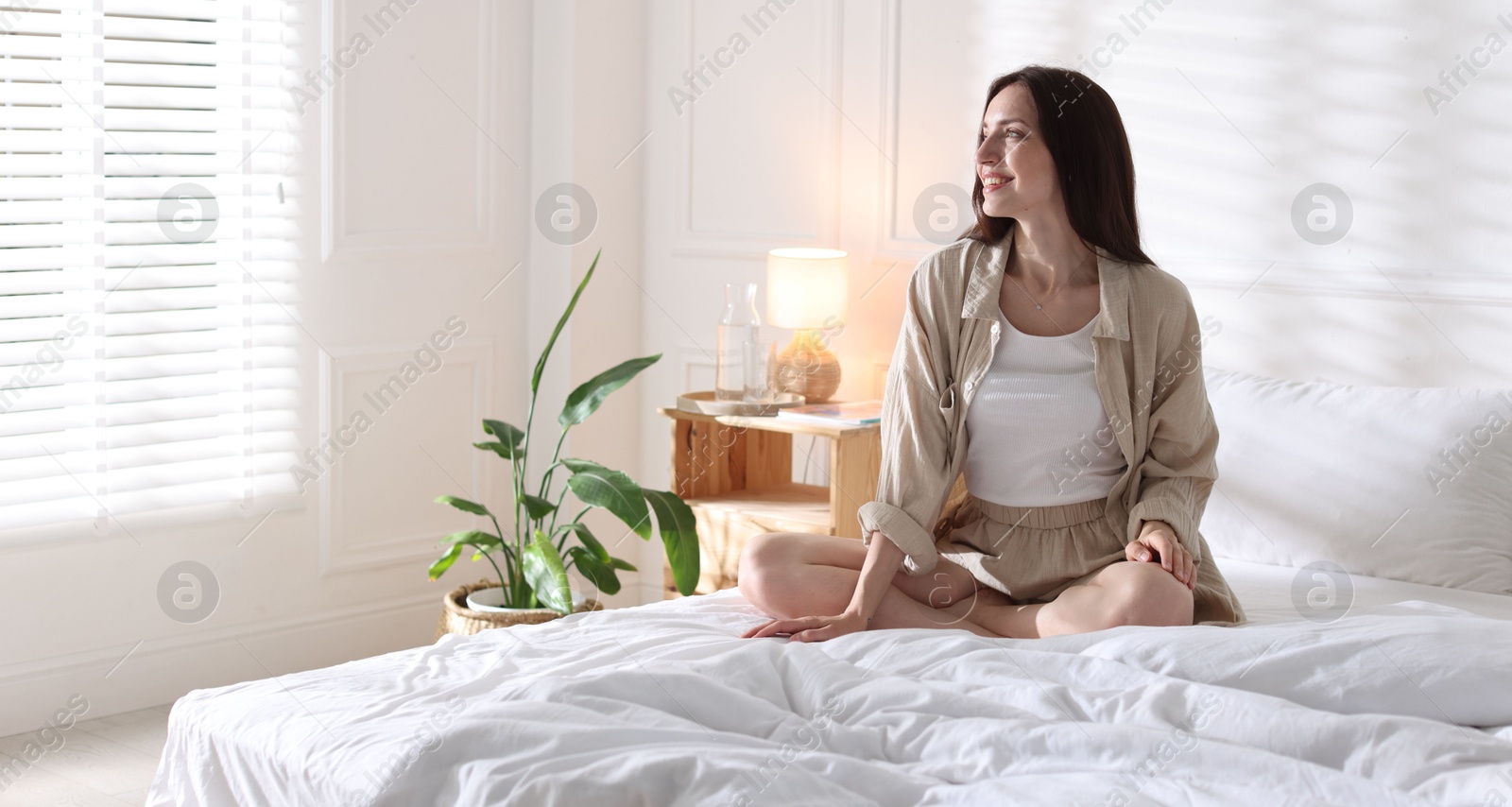 Woman on bed with soft mattress at home. Space for text Photo of Woman on bed with soft mattress at home. Space for text