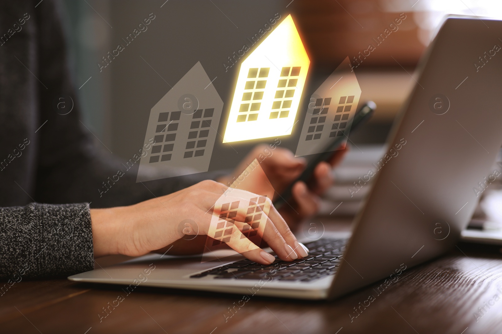 Image of Real estate agent looking for housing via laptop at table, closeup. Illustrations of buildings over device