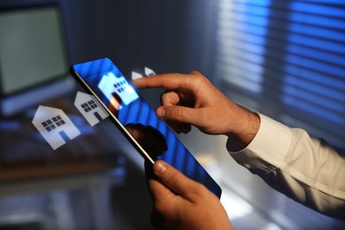 Image of Real estate agent touching house icon on tablet screen indoors, closeup. Search for apartment