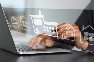 Image of Real estate agent touching house icon on virtual screen above laptop at table, closeup. Search for housing