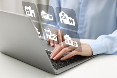 Image of Real estate agent looking for housing via laptop at white table, closeup. Illustrations of different dwellings over device