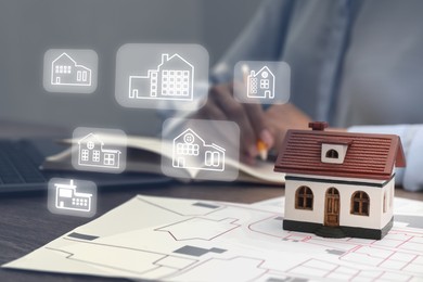 Image of Real estate agent looking for housing indoors, closeup. Different buildings icons over table