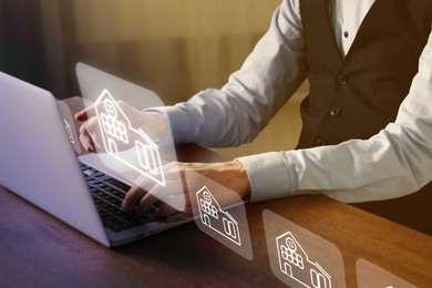 Image of Real estate agent looking for housing via laptop at wooden table, closeup. Illustrations of different buildings over device