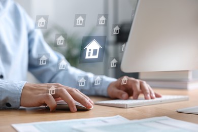 Image of Real estate agent looking for housing on computer, closeup. Illustrations of buildings over desk