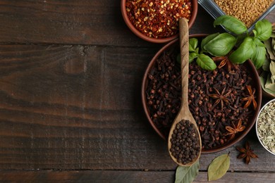 Photo of Different aromatic spices on wooden table, flat lay. Space for text