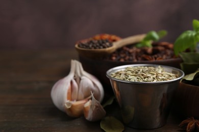 Photo of Different aromatic spices on wooden table against brown background, closeup. Space for text