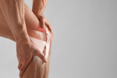 Image of Anatomy of knee. Man with illustration on his leg against grey background, closeup. Space for text