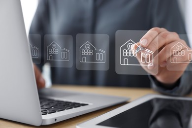Image of Real estate agent touching house icon on virtual screen at table, closeup. Search for housing