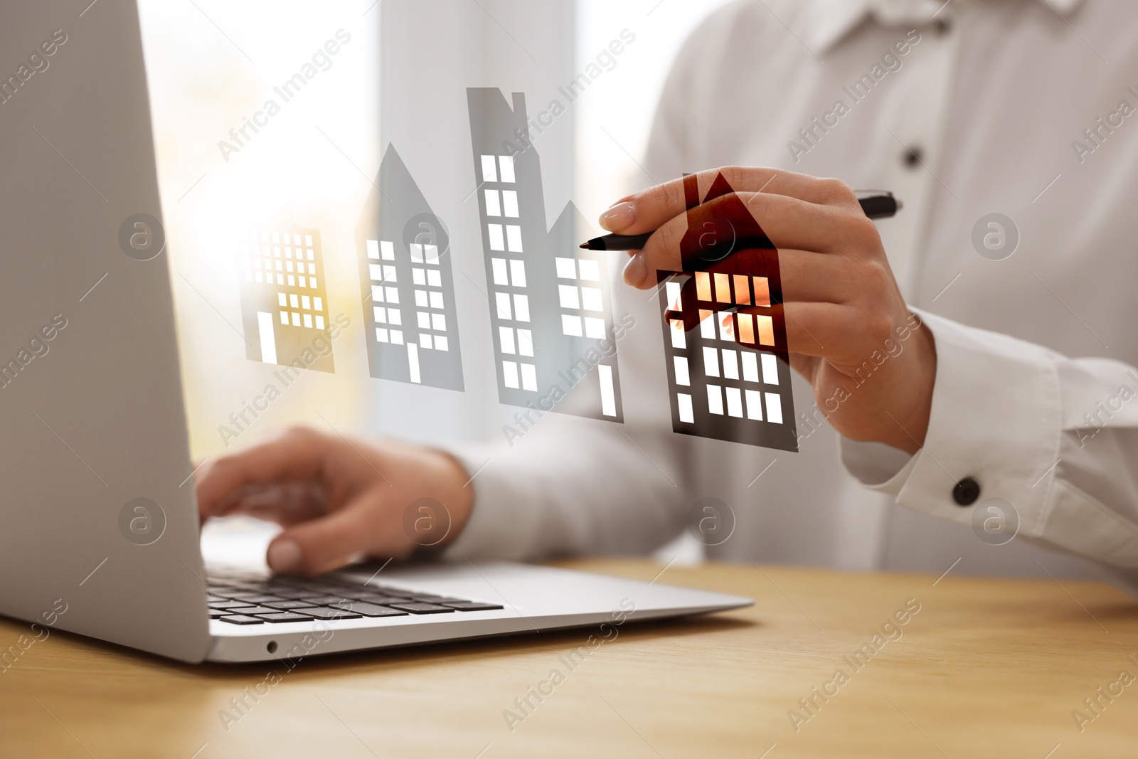 Real estate agent touching house icon on virtual screen while working on laptop at table, closeup. Search for housing Image of Real estate agent touching house icon on virtual screen while working on laptop at table, closeup. Search for housing