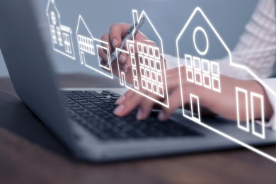 Image of Real estate agent touching house icon on virtual screen above laptop at wooden table, closeup. Search for housing