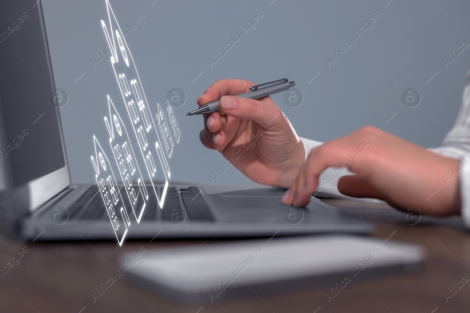 Real estate agent touching house icon on virtual screen above laptop at table, closeup. Search for housing Image of Real estate agent touching house icon on virtual screen above laptop at table, closeup. Search for housing