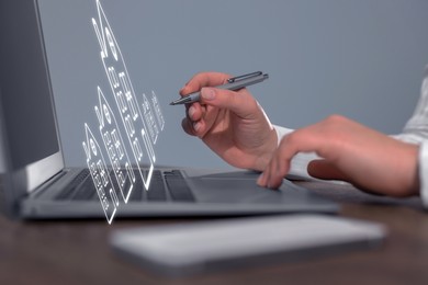 Image of Real estate agent touching house icon on virtual screen above laptop at table, closeup. Search for housing