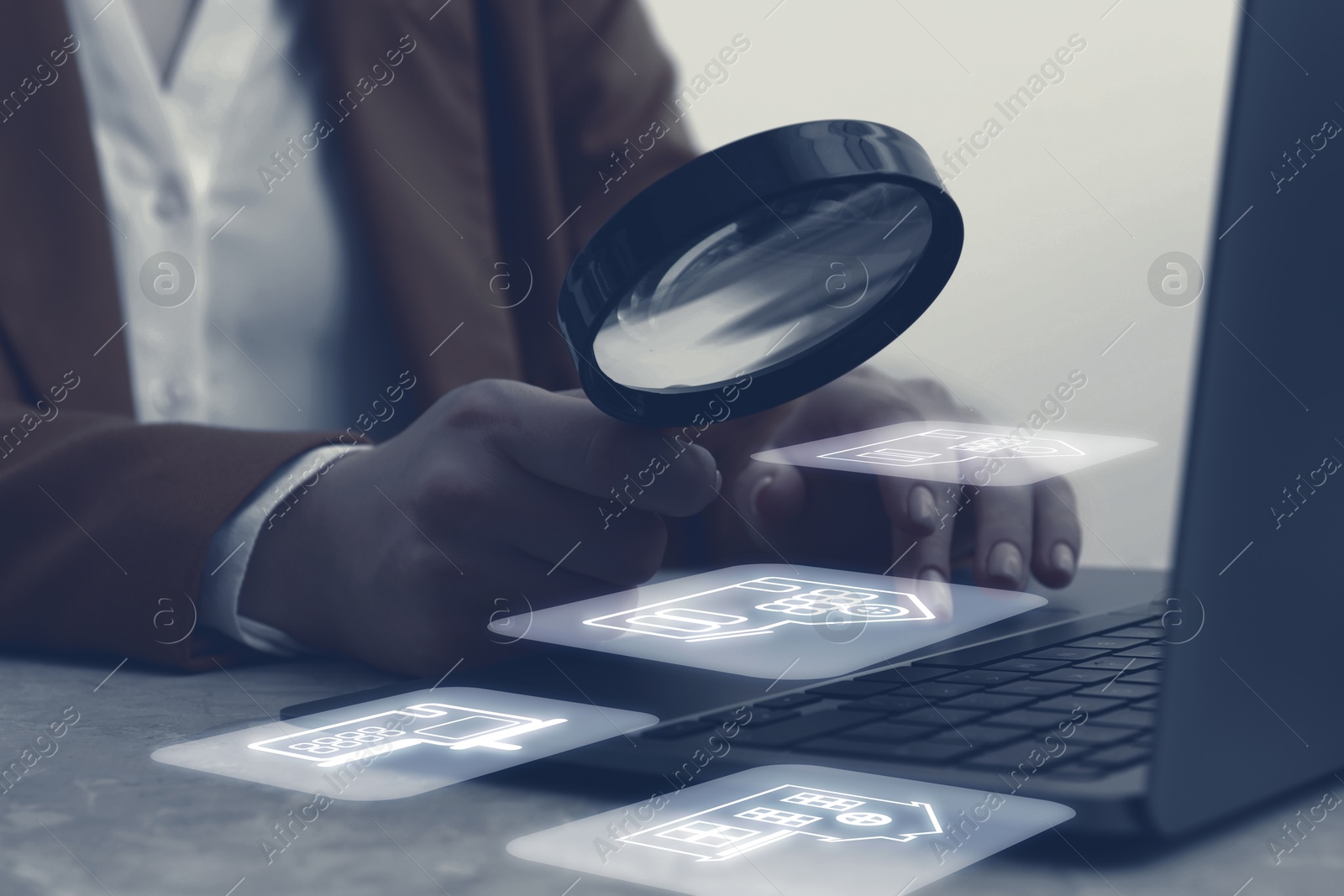 Image of Real estate agent looking at buildings icons with magnifying glass over laptop, closeup. Search for housing