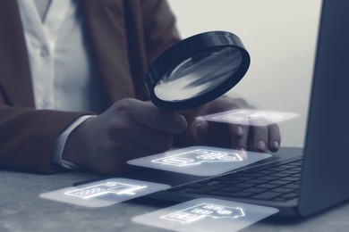 Image of Real estate agent looking at buildings icons with magnifying glass over laptop, closeup. Search for housing
