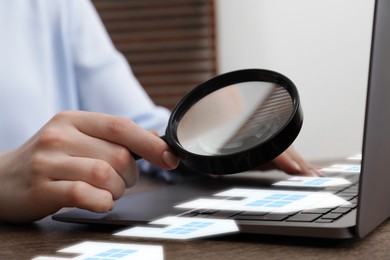 Image of Real estate agent looking at buildings icons with magnifying glass over laptop, closeup. Search for housing