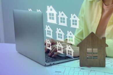 Image of Real estate agent looking for housing via laptop at table, closeup. Different buildings icons over device