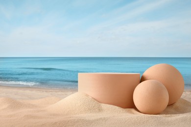 Image of Podium for product presentation. Figures on sand near blue sea. Stylish promotion poster