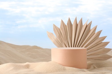 Image of Podium for product presentation with dry palm leaf on sand. Stylish promotion poster