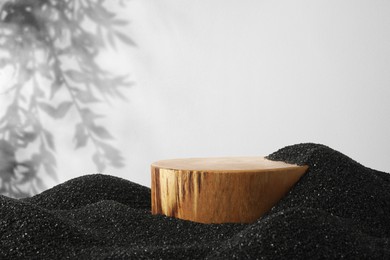 Image of Podium for product presentation on black sand against white background with shadow. Stylish promotion poster