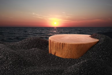 Image of Podium for product presentation on black sand against seascape at sunset. Stylish promotion poster